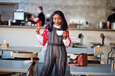 Kafede rahat giyinen, kendinden emin, Afro-Amerikan bir kadın.. 