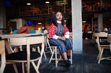 Kafede rahat giyinen, kendinden emin, Afro-Amerikan bir kadın.. 