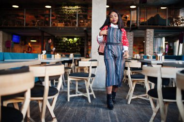 Kafede rahat giyinen, kendinden emin, Afro-Amerikan bir kadın.. 