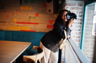 Çekici Afrikalı Amerikalı kadın manken siyah ceketli ve boş zamanlarında kafede dinleniyor..