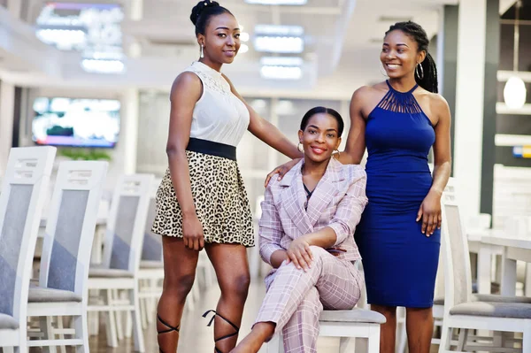 Three african woman in dress posing at restaurant.