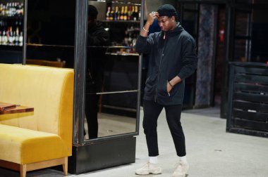 Siyah şapkalı, gece kulübünün içinde poz veren yakışıklı Afrikalı Amerikalı..