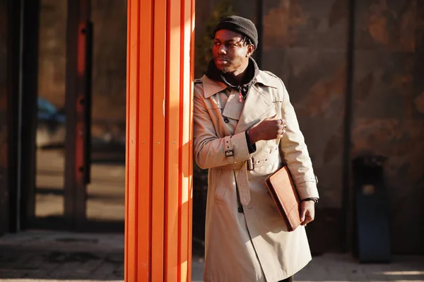 ハンサムなアフリカ系アメリカ人の男は黒の帽子とベージュのコートで外にポーズでフォルダを手 — ストック写真