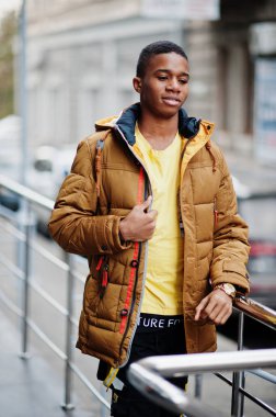 Afrikalı adam soğuk havada açık havada turuncu ceket giyer..