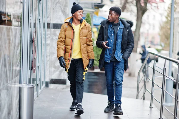 Two african male friends talking together, wear on jackets at cold weather.