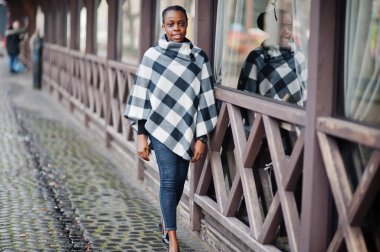 Kareli pelerinli Afrikalı kadın dışarıda poz verdi..