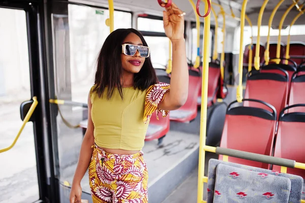 Young stylish african american woman in modern sunglasses riding on a bus.
