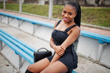 Stadyumdaki tribünde siyah giyinmiş şık, seksi, Afro-Amerikalı bir kadın..