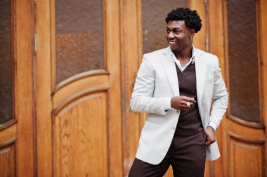 Düşünceli, genç, yakışıklı, Afro-Amerikalı, resmi giysili bir beyefendi. Beyaz ceketli, siyah şık bir adam..