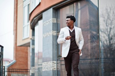 Düşünceli, genç, yakışıklı, Afro-Amerikalı, resmi giysili bir beyefendi. Beyaz ceketli, siyah şık bir adam..