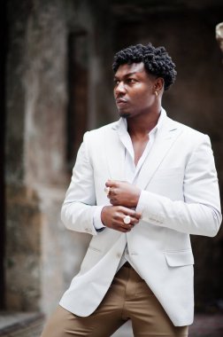 Düşünceli, genç, yakışıklı, Afro-Amerikalı, resmi giysili bir beyefendi. Beyaz ceketli, siyah şık bir adam..