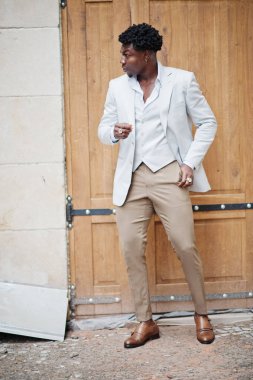 Düşünceli, genç, yakışıklı, Afro-Amerikalı, resmi giysili bir beyefendi. Beyaz ceketli, siyah şık bir adam..