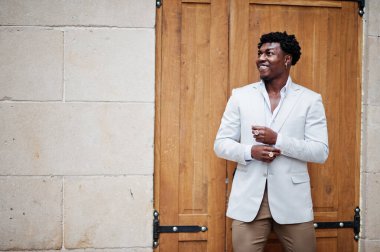 Düşünceli, genç, yakışıklı, Afro-Amerikalı, resmi giysili bir beyefendi. Beyaz ceketli, siyah şık bir adam..