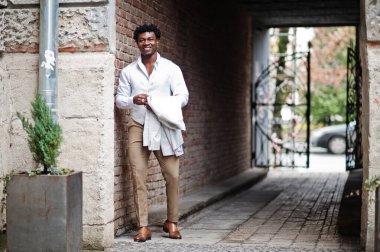 Düşünceli, genç, yakışıklı, Afro-Amerikalı, resmi giysili bir beyefendi. Beyaz ceketli, siyah şık bir adam..