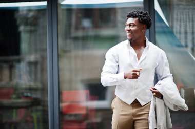 Düşünceli, genç, yakışıklı, Afro-Amerikalı, resmi giysili bir beyefendi. Beyaz ceketli, siyah şık bir adam..