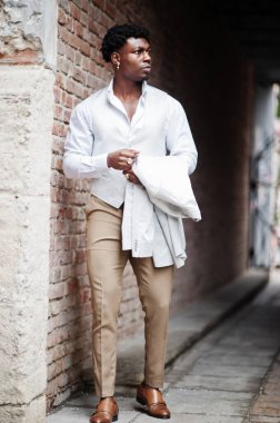 Düşünceli, genç, yakışıklı, Afro-Amerikalı, resmi giysili bir beyefendi. Beyaz ceketli, siyah şık bir adam..