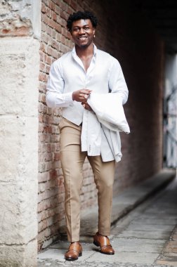 Düşünceli, genç, yakışıklı, Afro-Amerikalı, resmi giysili bir beyefendi. Beyaz ceketli, siyah şık bir adam..