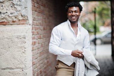 Düşünceli, genç, yakışıklı, Afro-Amerikalı, resmi giysili bir beyefendi. Beyaz ceketli, siyah şık bir adam..