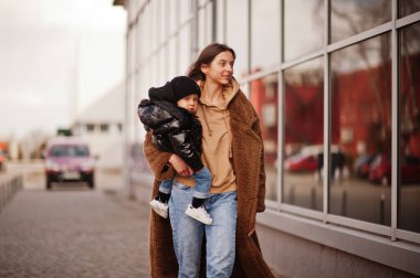 Ellerinde çocukla sokaklarda yürüyen genç bir anne..
