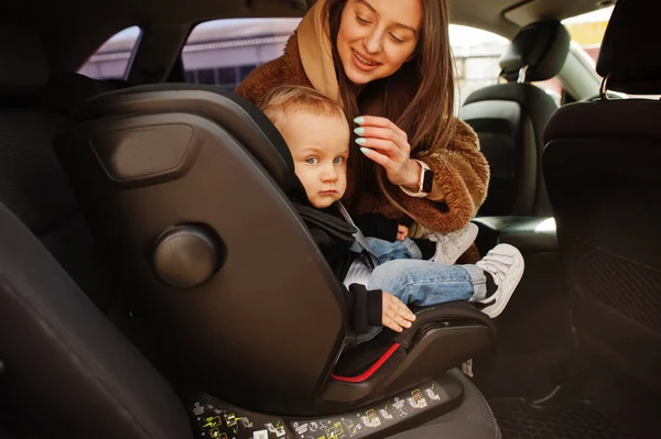 Young mother and child in car. Baby seat on chair. Safety driving concept.