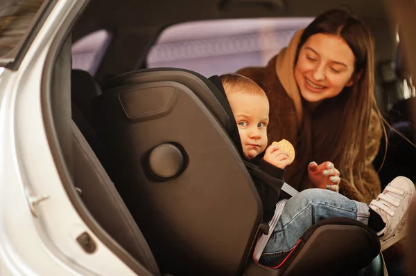 Young mother and child in car. Baby seat on chair. Safety driving concept.