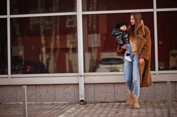 stock image Young mother with child on hands walking down streets.