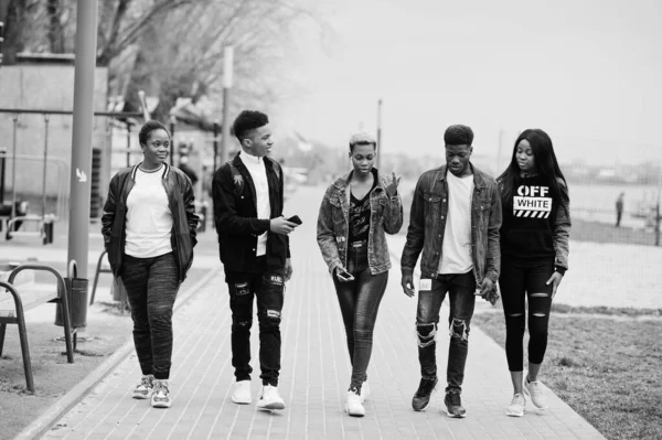 Young millennials african friends walking in city. Happy black people having fun together. Generation Z friendship concept.