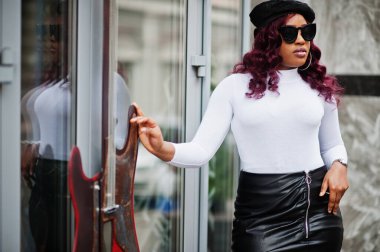 Büyük anne ve siyah güneş gözlüklü, bereli ve deri etekli Afro-Amerikan modeli açık havada poz verdiler..