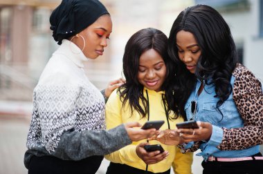 Cep telefonlu üç üniversiteli Afrikalı Amerikalı kadın arkadaş..