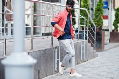 Sokakta güneş gözlükleriyle poz veren genç Hintli adam portresi..