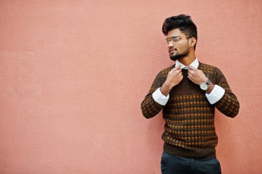 Pembe duvar arkasında izole edilmiş gözlüklü genç Hintli adam portresi..