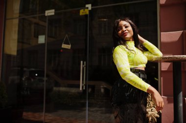 Genç, güzel, Afro-Amerikan model kadın portresi, yeşil bluz ve siyah, ıslak pantolon giyiyor..