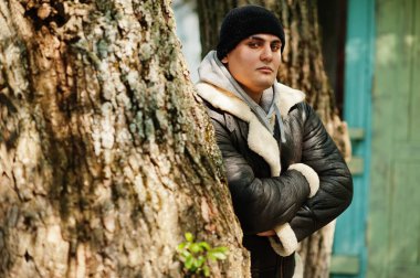 Deri ceketli ve siyah şapkalı ciddi bir Arap, aksiyon filminden idolünü kopyalıyor..