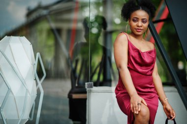 Afro saçlı, güzel, doğal bir Afrikalı kadının portresi. Kırmızı ipek elbiseli siyah model..