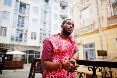 Siyah bir gencin portresi, Afrikalı geleneksel kırmızı renkli kıyafetler giyiyor..