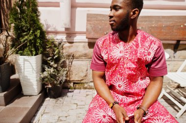 Siyah bir gencin portresi, Afrikalı geleneksel kırmızı renkli kıyafetler giyiyor..