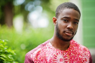 Siyah bir gencin portresi, Afrikalı geleneksel kırmızı renkli kıyafetler giyiyor..