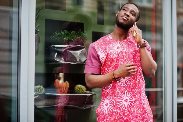 Siyahi bir gencin portresi, Afrikalı geleneksel kırmızı renkli giysiler ve cep telefonu..