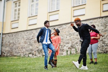 Dört Afrikalı arkadaş dışarıda eğleniyor ve dans ediyor. İki siyah kız ve erkekler..