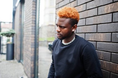 Afrikalı kızıl saçlı adam dışarıda poz veren siyah elbiseler giyiyor..