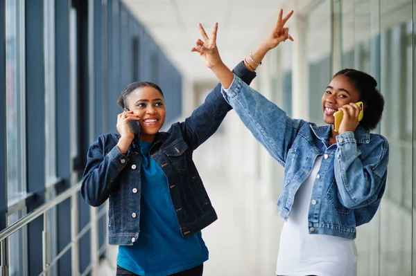 Kot Ceketli Iki Afrikalı Kadın Telefonda Eller Içeride Birlikte Konuşuyor — Stok fotoğraf