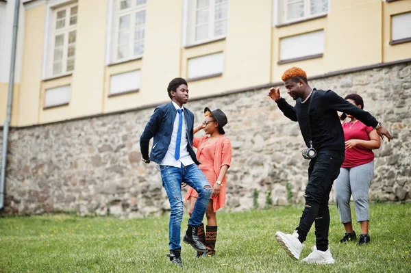 Dört Afrikalı arkadaş dışarıda eğleniyor ve dans ediyor. İki siyah kız ve erkekler..