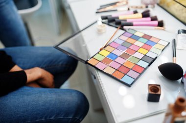 Afro-Amerikalı bir kadın güzellik salonunda makyaj sanatçısı tarafından makyaj yapıyor..