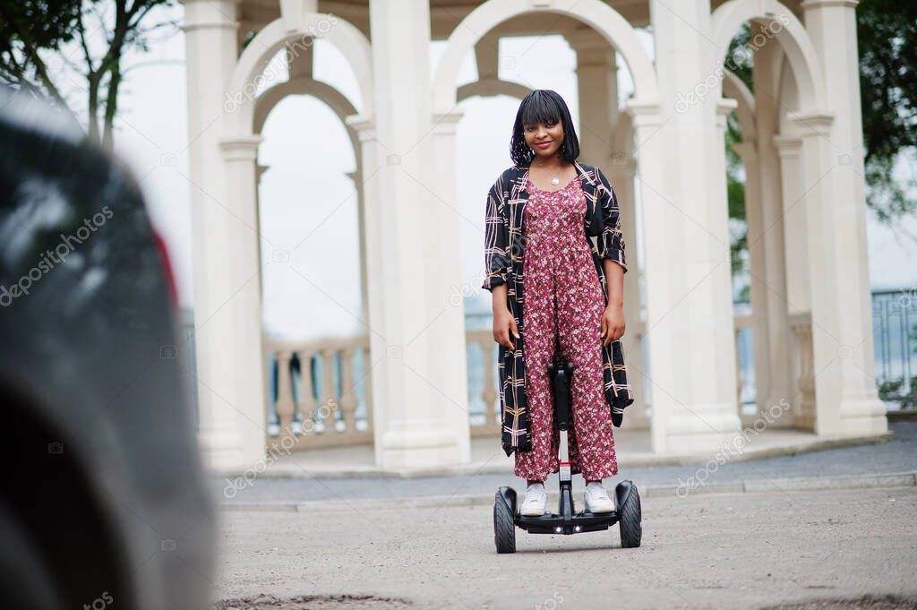 Beautiful african american woman using segway or hoverboard. Black girl on dual wheel self balancing electrical scooter.