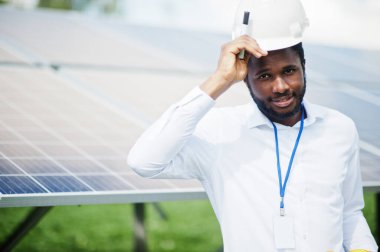 Afrikalı Amerikalı teknisyen güneş panellerinin bakımını kontrol ediyor. Güneş istasyonundaki siyah adam mühendisi..