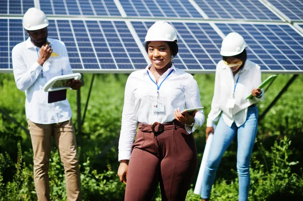 African american technician checks the maintenance of the solar panels. Group of three black engineers meeting at solar station.