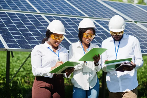 African american technician checks the maintenance of the solar panels. Group of three black engineers meeting at solar station.