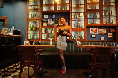 Afro-Amerikan kadın portresi, restoranda bir fincan latte ile eski moda saç modeli..