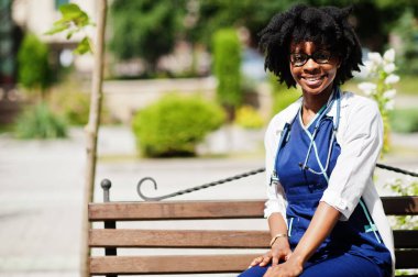 Steteskoplu, laboratuvar önlüğü giyen Afrikalı Amerikalı kadın doktorun portresi..