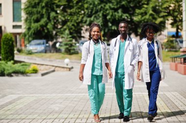 Steteskoplu üç Afrikalı Amerikalı grup doktoru laboratuvar önlüğü giyiyor..